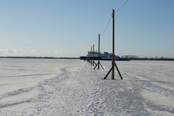 ship breaks ice on a frozen river for other ships. crosses a pedestrian crossing to the other side