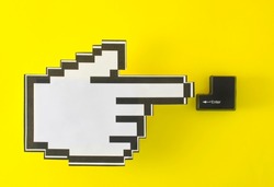 the mouse cursor hand points to the black enter button from the keyboard. yellow background. copy space.