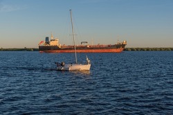 yacht on the Severnaya Dvina River on a summer evening against the background of a cargo ship. copy space.
