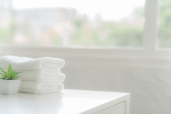 white cotton towels on white counter table inside a bright bathroom background. For product display montage.
