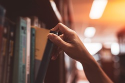 
Image of a hand selecting a book from a bookshelf
