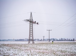 Utility workers repair a powerline during snowfall early in the morning