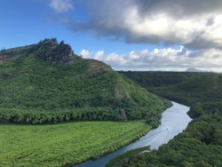 Close up of A round high round mountain covered with trees on the horizon. Panorama Aerial scene view of a mountain river with a boat sailing. kamokila hawaiian village, Kauai, Hawaii islands, U.S.A
