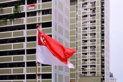 Singapore flag waving in the wind against background of HDB flats. Selective focus