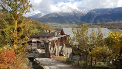 Image of an old, rustic, Swiss-German hut with house attached on a narrow decending path next to a small stream with the impressive valais mountains in the background, taken in Naters, near Brig.