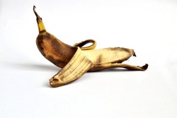 On a white background lies a banana that has not been completely peeled. The banana peel has dark spots. The banana is overripe.