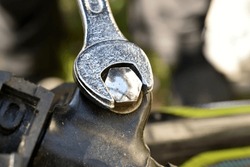 A close-up of an open-end wrench used to tighten a bicycle handlebar bolt.