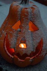 Candle burning in a snow covered jack o lantern