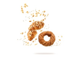 Fresh baked turkish simit sesame bagel, french butter almond nut croissants flying falling with seeds, flakes and crumbs isolated on white background. Pastry shop card