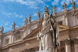 Statue of Apostle Paul in front of the St Peter's Basilica, Vatican, Rome, Italy. Detail of the facade exterior on the blue sky background. Renaissance sculpture of the Apostle Paul with a sword.