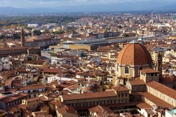 Beautiful red rooftops of ancient houses and streets of Florence, Italy. Aerial view of Firenze on a sunny day. Panoramic view of Basilica of San Lorenzo and Train station.