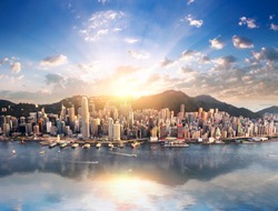 Hong Kong skyline. Hongkong hdr aerial cityscape with sunset sun. Amazing panorama of buildings and sky reflecting in harbour