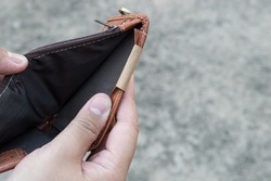 Broke man showing his brown leather wallet with no money on a poor economy day