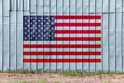 an american flag painted metal warehouse farm steel building wall faded weathered america pride holiday patriotism symbol