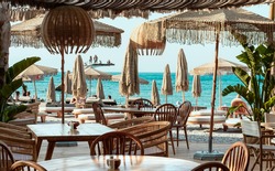 Beach  club view, modern white sun beds, knitted makrome umbrellas for sun protection, sea on background, food corner tables