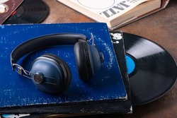 Large blue headphones on a stack of vintage vinyl records, next to a book titled Jazz. Concept of listening to jazz vinyl records. Selective focus.
