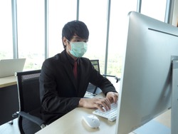 Asian business man or employee wear medical mask is working on his computer desktop.Office personal wok at home to avoid disease of corona virus covid19.