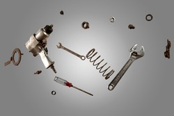 Old tool set includes: drill, wrench, screwdriver, spring, screw, nail, burr. Isolated on gray background.