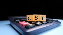 GST or Goods and Services Tax by letters on wooden beads or blocks and calculating GST with calculator.
