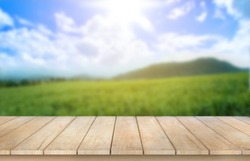 Wooden table top on blur mountain and grass field background in morning or evening atmosphere.For montage product display or design key visual layout.view of copy space.