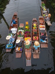 Peoples sell agriculture fruit and food on wooden boat at Damnoen Saduak Floating Market is popular tourist attraction on canals of Thailand.
