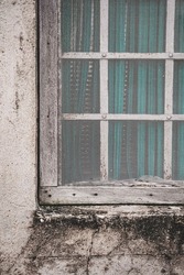A barred old window with a white mosquito net.