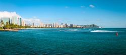 Cityscape panorama of Waikiki Beach shoreline with Diamond Head on Oahu in the distance.