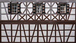 Old, partly weathered model building half-timbered house facade with three windows in close-up