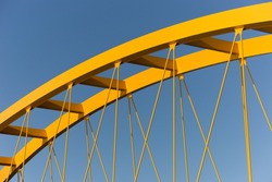 Yellow steel cable stayed bridge against a steel blue sky