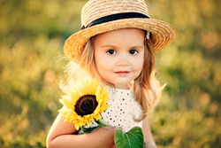 
girl in a hat with a sunflower, summer portrait of a child, beautiful eyes