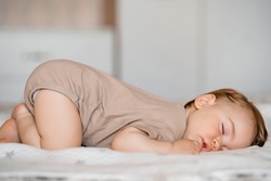 Funny baby with open mouth sleeping on his stomach on the bed at home. High quality photo