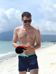 Young tourist man smiles at Doc Let beach of Vietnam with white sand