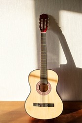 A brown wooden classic guitar with shadow. Six strings.