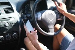 male driver behind the wheel looking at the phone in his hand