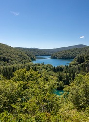 Plitvice Lakes National Park, Coratia: Pamoramic image of the upper lakes with blue sky on a hot summer day. No clouds and lush green forest.