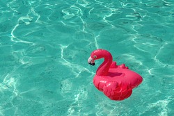 Pink, inflatable beach flamingo on the background of turquoise water. Hit of the summer