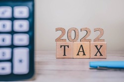 TAX 2022 on wooden cubes, calculator and a pen on a wooden table. Tax 2022 - phrase from wooden blocks with letters, Tax time 2022 concept
