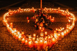 Memorial gathering on remembrance day.Many burning candles shape of heart.Candles Burning at Night.Solemn sad occasion background.Candle flames glowing in dark, spiritual meditation piety atmosphere
