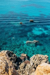Two people snorkling in turquoise Mediterranean Sea,Malta.Aerial view of swimming people.Relax vacation concept.Crystal clear ocean.Snorkeler explores reefs.Malta beach top view.Active summer holiday
