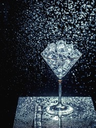ice cubes are not a dark table. martini glasses on dark background. martini ice on a dark table. martini glasses and water splashes. water drops and martini on dark background