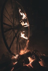 an old wheelchair burning in a fire with flames in the wheels in the dark
