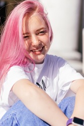 Portrait of a positive pink-haired teenage girl in a white T-shirt and blue jeans.Street style.Summer concept.Generation Z style.