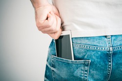 Male Hand Grabbing A Smartphone In The Left Back Pocket Of A Jeans Trouser