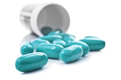 Blue pills an pill bottle on white background