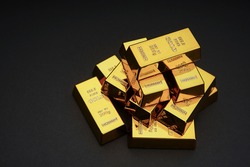 A pile of gold bar a black background. Shiny precious metals for investments or reserves.