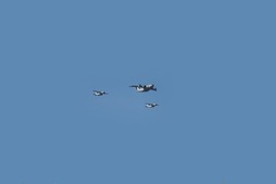 Group of three specialized transport aircraft flying in formation during an air force display with blue sky as background.