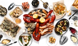 Lobster and seafood party table with oyster, crab, clams, shrimps and crayfish on white tablecloth photographed from above