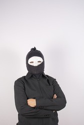 Portrait of woman in balaclava standing with arms crossed.