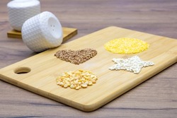 Peas, pearl barley, buckwheat, corn grits on a brown wooden table. Gluten free porridge. Heart shape, circle and asterisk