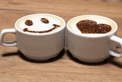 Two cups of cappuccino with trendy heart and latte art smile. Coffee for a couple in love